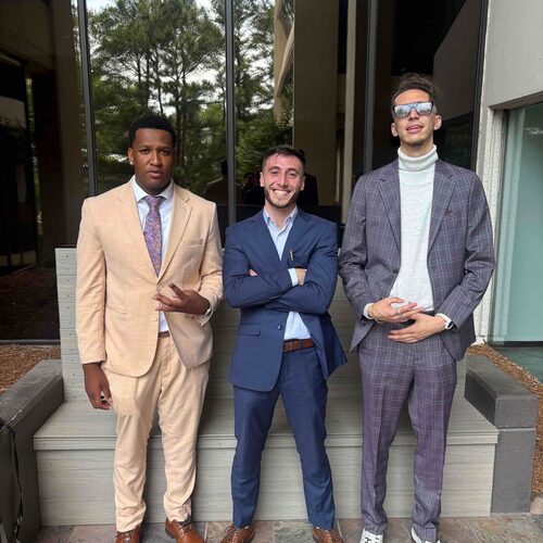 Three Winners Crest Agency team members in tailored suits outside a client office