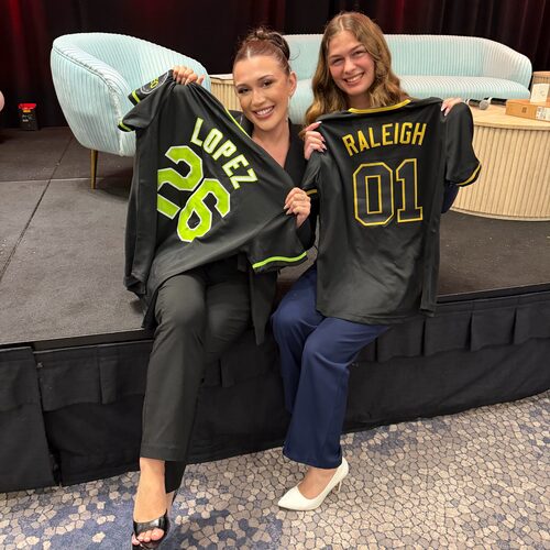Two Winners Crest Agency team members holding personalised team jerseys at a recognition event